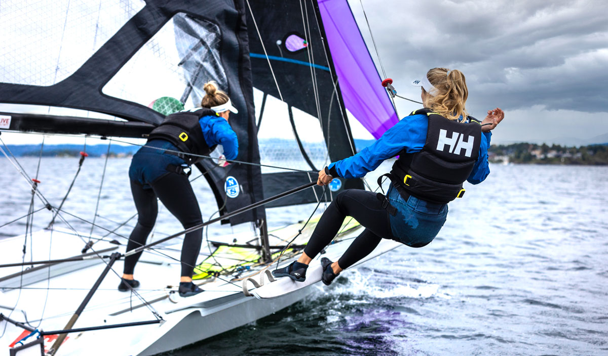 Two sailors trapezing from a high-performance skiff dinghy under sail on choppy water