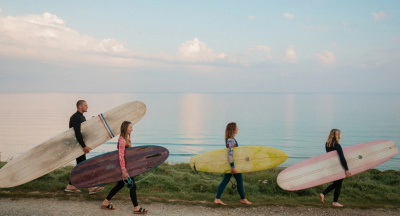 Surfers heading into the water in summer wetsuits