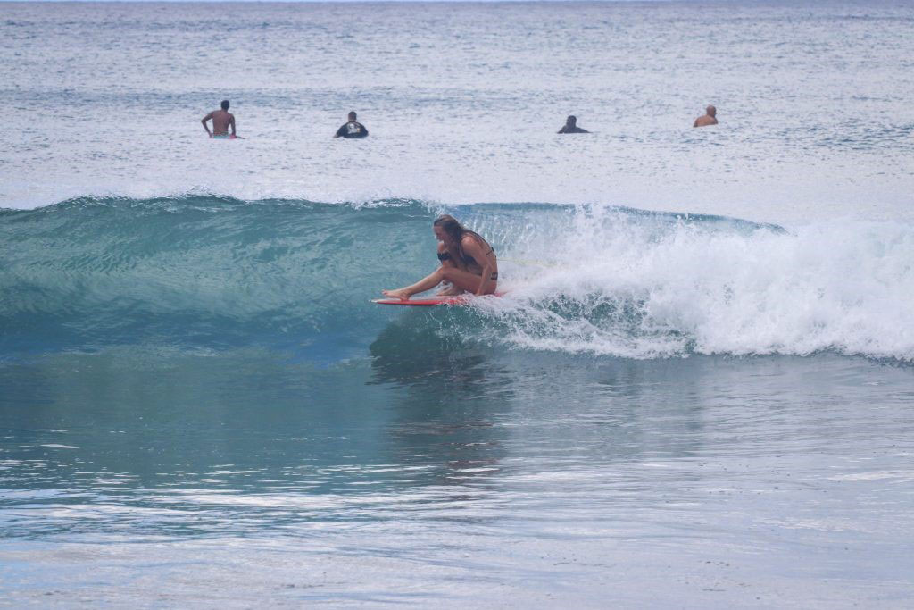 Surfer riding a small clean wave while others wait in the line-up behind