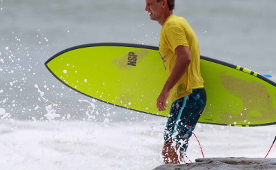 Man running into the sea with a surfboard