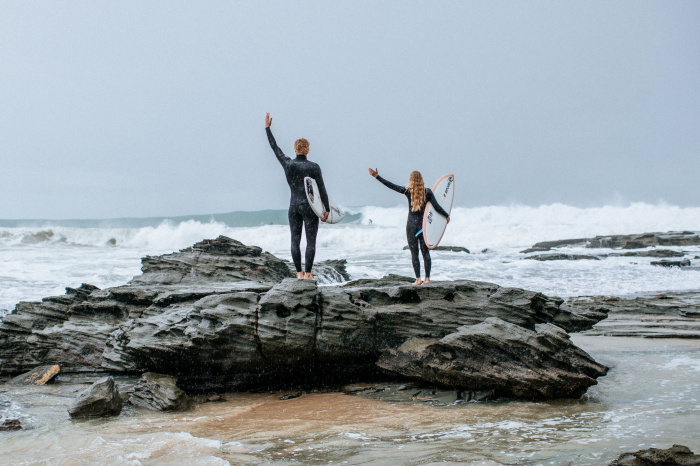 Surfer wearing a Rip Curl Trad wetsuit carrying a board into the surf
