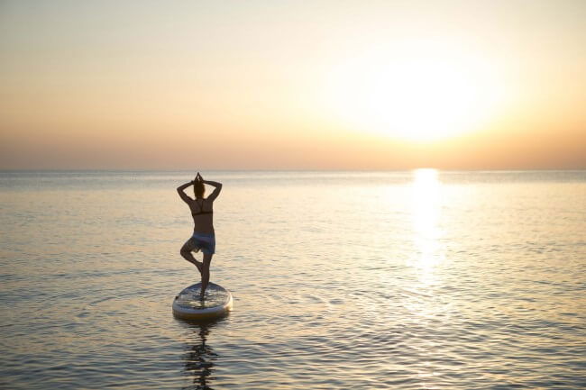 Woman doing yoga on a Red Paddle Co SUP board